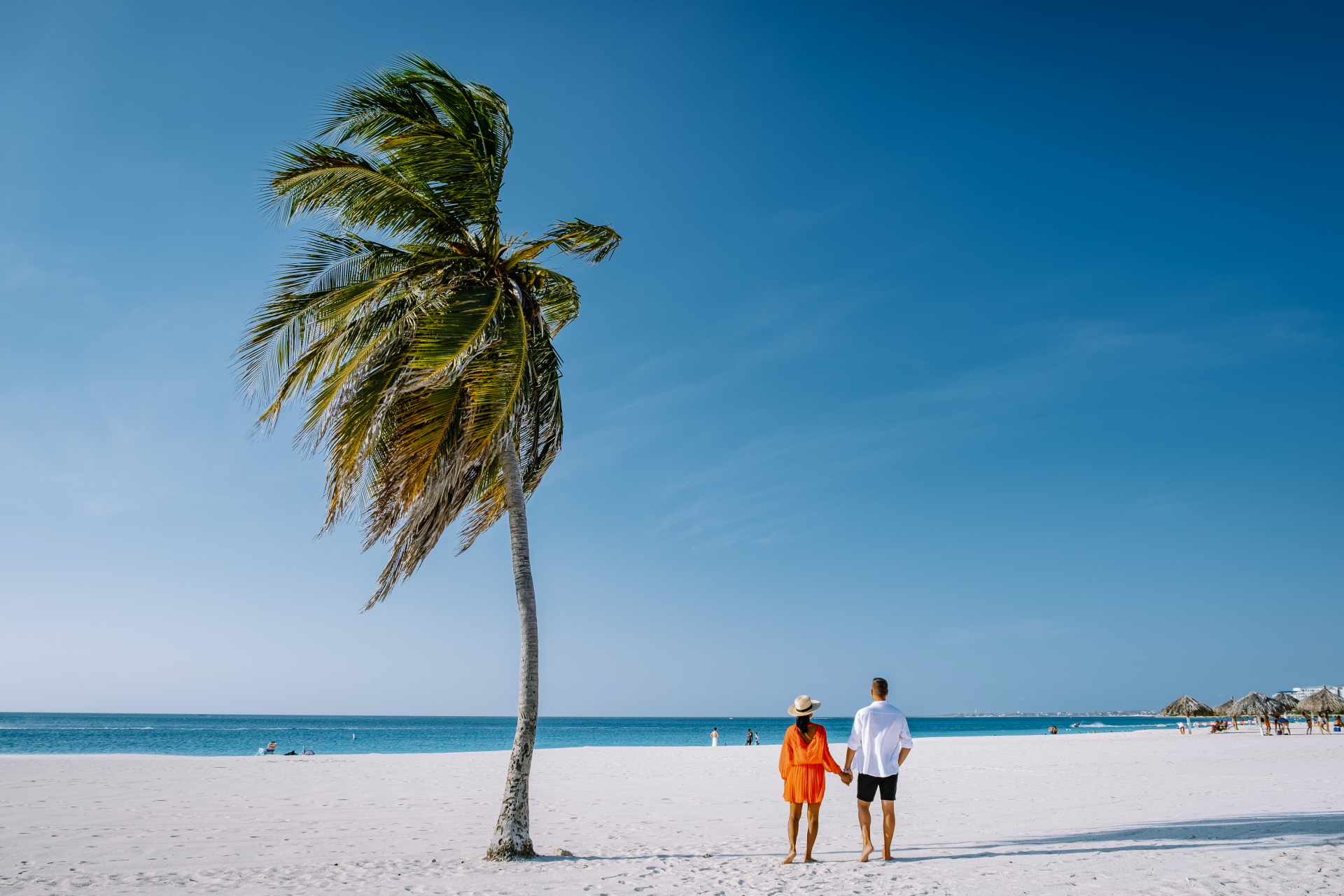 Couple on vacation, holding hands on the sunny beach in Aruba
